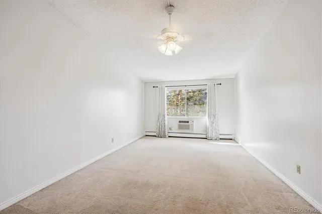 an empty room with a chandelier fan and windows
