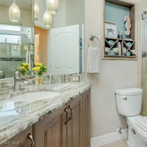 a bathroom with a granite countertop sink a toilet and mirror