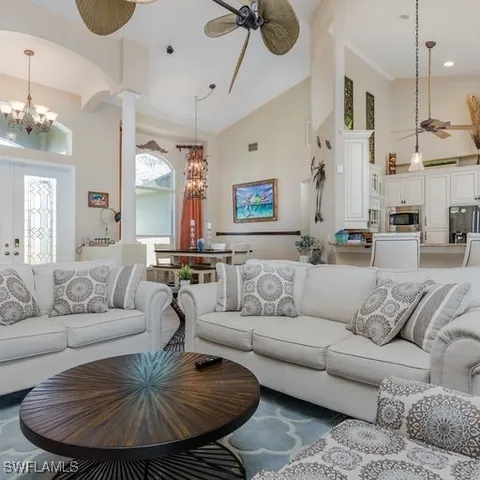 a living room with furniture kitchen view and a chandelier