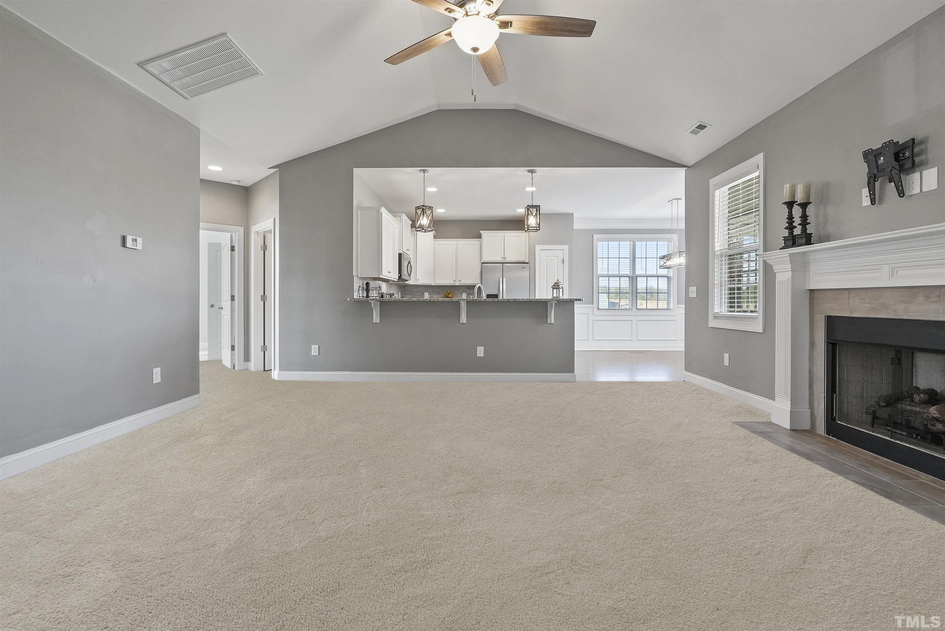 4085 Old 75 Highway Stem, NC 27581 - Photo 8 of 36 a livingroom with a fireplace a ceiling fan and a kitchen view