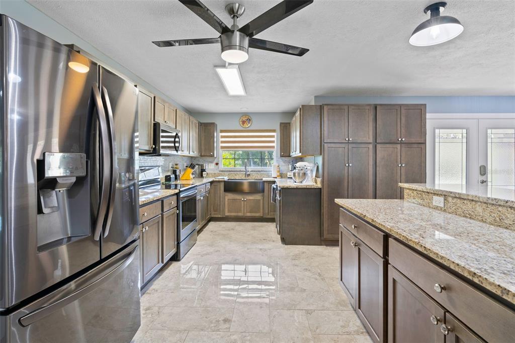 965 North Appalachian Terrace Crystal River, FL 34429 - Photo 12 of 65 a kitchen with stainless steel appliances granite countertop a refrigerator a sink dishwasher a stove with white cabinets and wooden floor