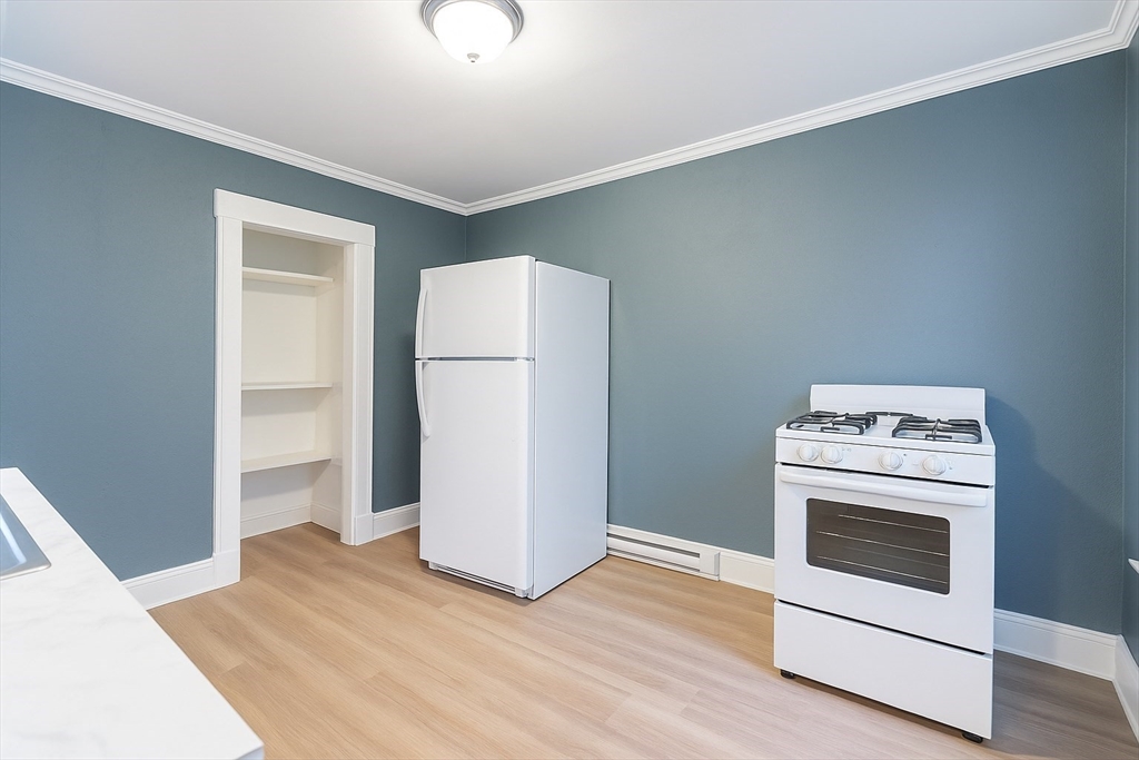 173 Elm Street, Unit 3LR Holyoke, MA 01040 - Photo 3 of 5 a kitchen with a stove a refrigerator and white cabinets