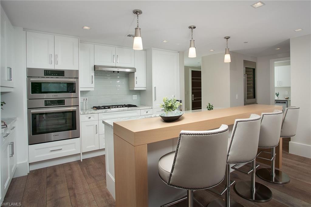 6897 Grenadier Boulevard, Unit 207 Naples, FL 34108 - Photo 11 of 27 a kitchen with stainless steel appliances kitchen island a table chairs sink and cabinets