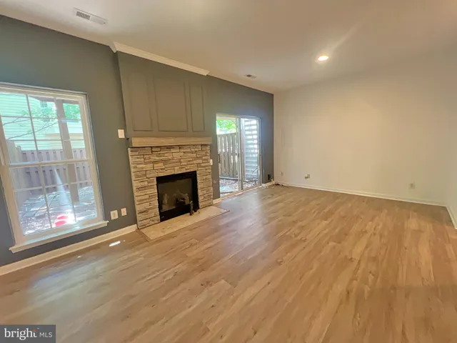 an empty room with wooden floor fireplace and windows