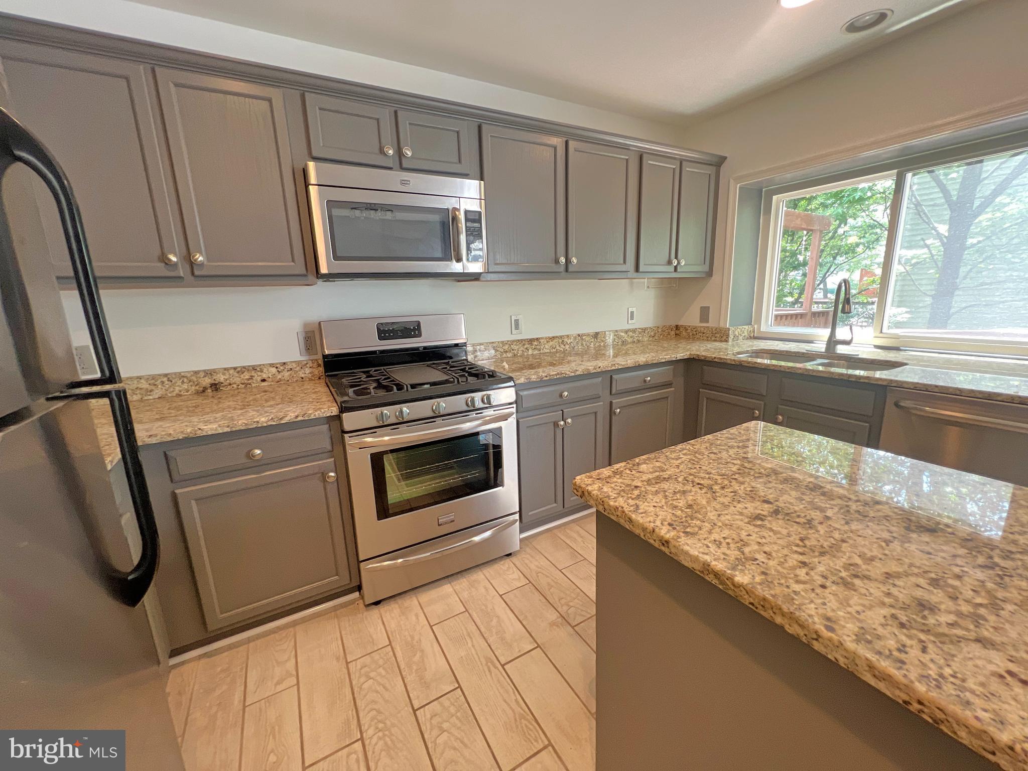 1191 Cypress Tree Place Herndon, VA 20170 - Photo 9 of 18 a kitchen with stainless steel appliances granite countertop a stove a sink and a microwave