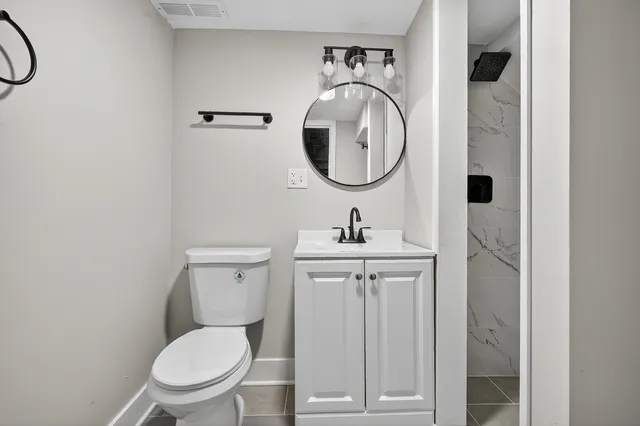 a bathroom with a toilet sink vanity and mirror