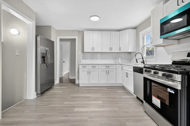 a kitchen with stainless steel appliances granite countertop a stove top oven a sink and a refrigerator