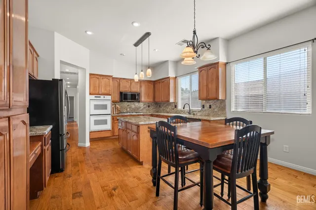 a kitchen with stainless steel appliances granite countertop a stove a refrigerator a oven a sink a dining table and chairs