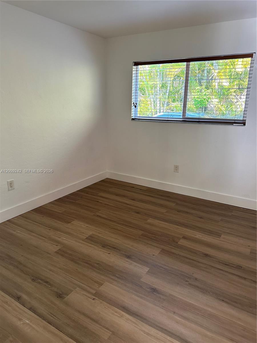 6310 Southwest 79th Street, Unit 1 South Miami, FL 33143 - Photo 3 of 8 a view of an empty room with wooden floor and a window