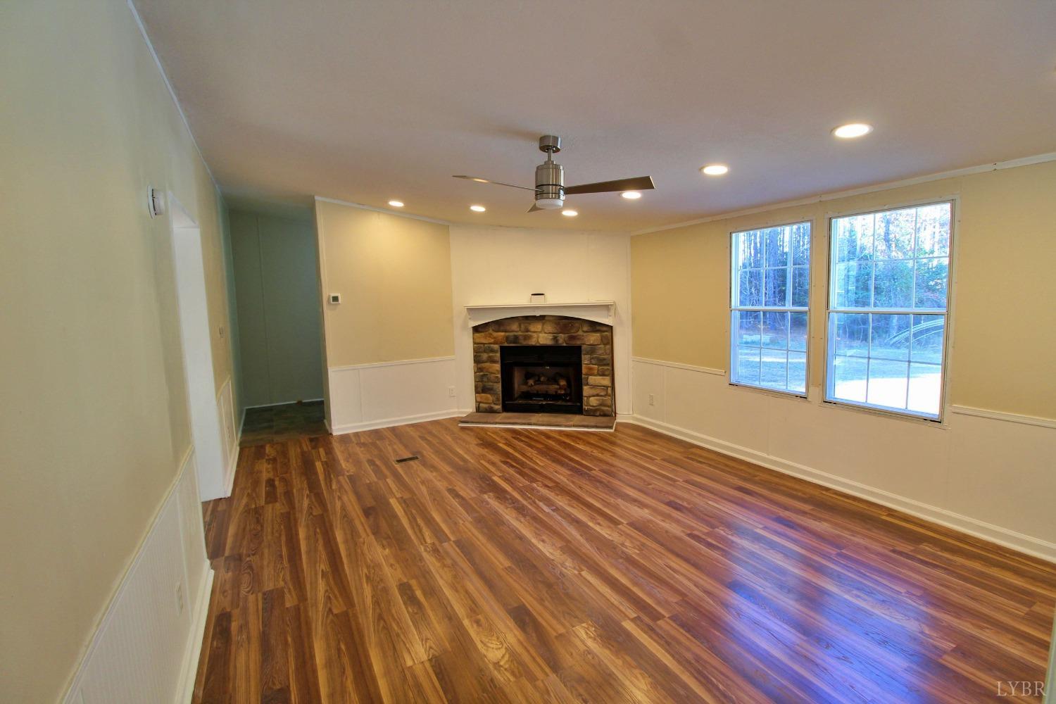 1908 Holiday Lake Road Appomattox, VA 24522 - Photo 12 of 35 an empty room with wooden floor fireplace and windows