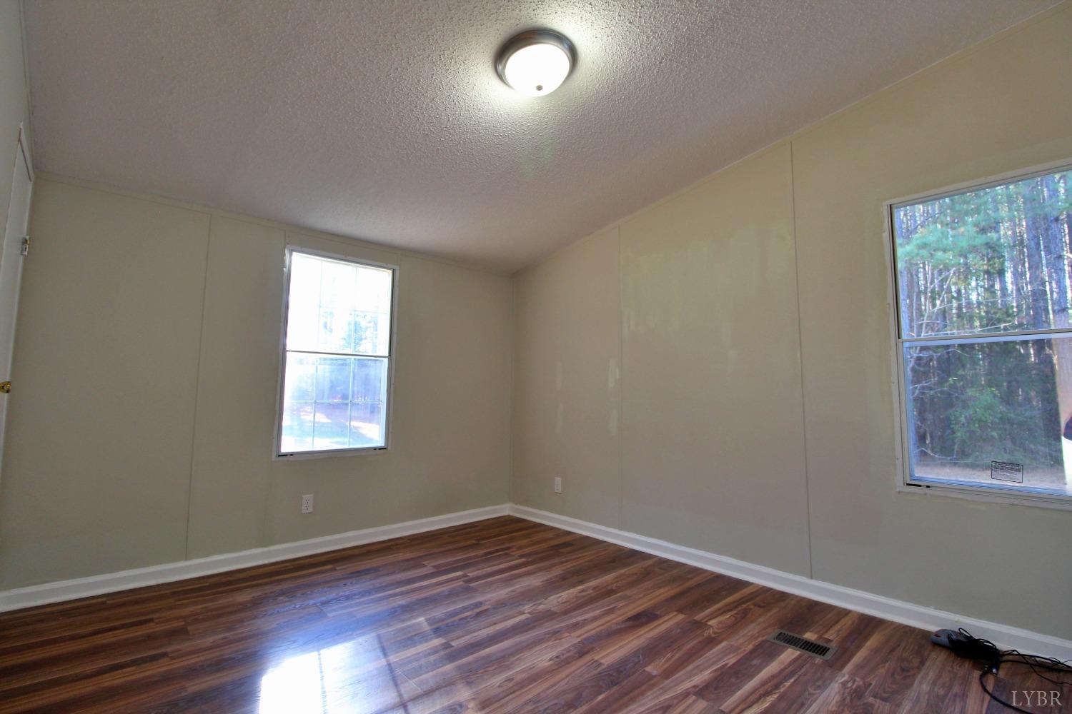1908 Holiday Lake Road Appomattox, VA 24522 - Photo 21 of 35 an empty room with wooden floor and windows