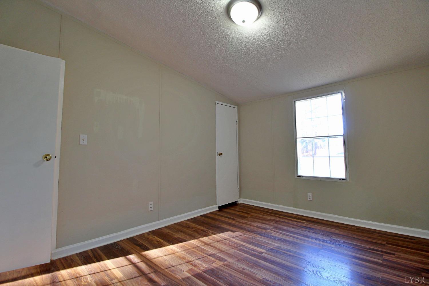 1908 Holiday Lake Road Appomattox, VA 24522 - Photo 22 of 35 an empty room with wooden floor and windows
