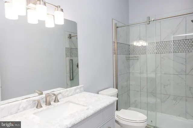 a bathroom with a granite countertop sink a toilet and shower
