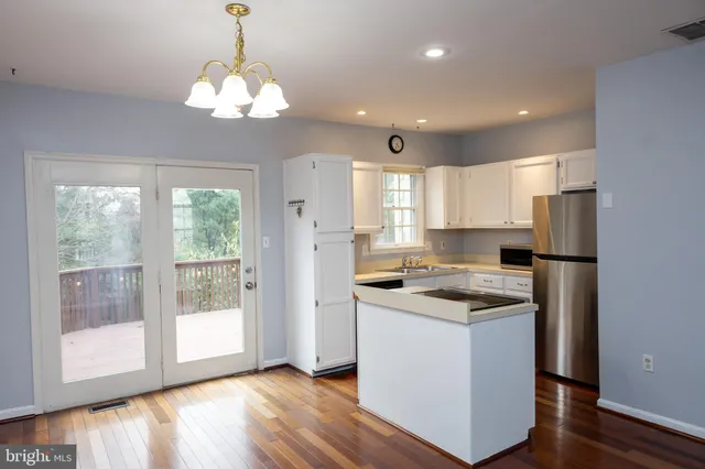 a kitchen with stainless steel appliances granite countertop a refrigerator a sink dishwasher a stove and white countertops with wooden floor