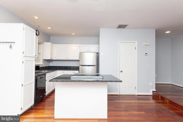 a kitchen with kitchen island stainless steel appliances granite countertop a refrigerator and a stove top oven