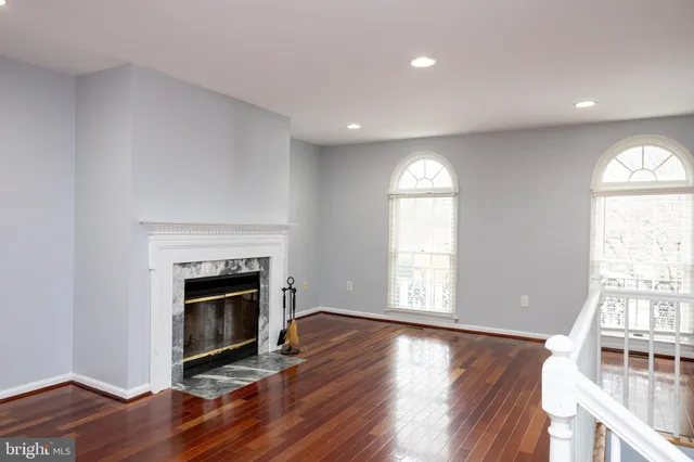 an empty room with wooden floor fireplace and windows