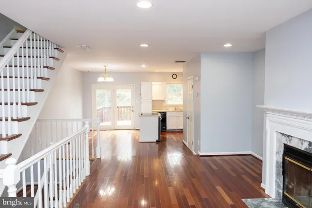 a view of a living room with wooden floor and a fireplace