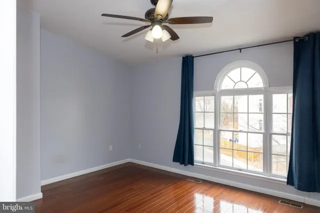 an empty room with wooden floor chandelier and windows