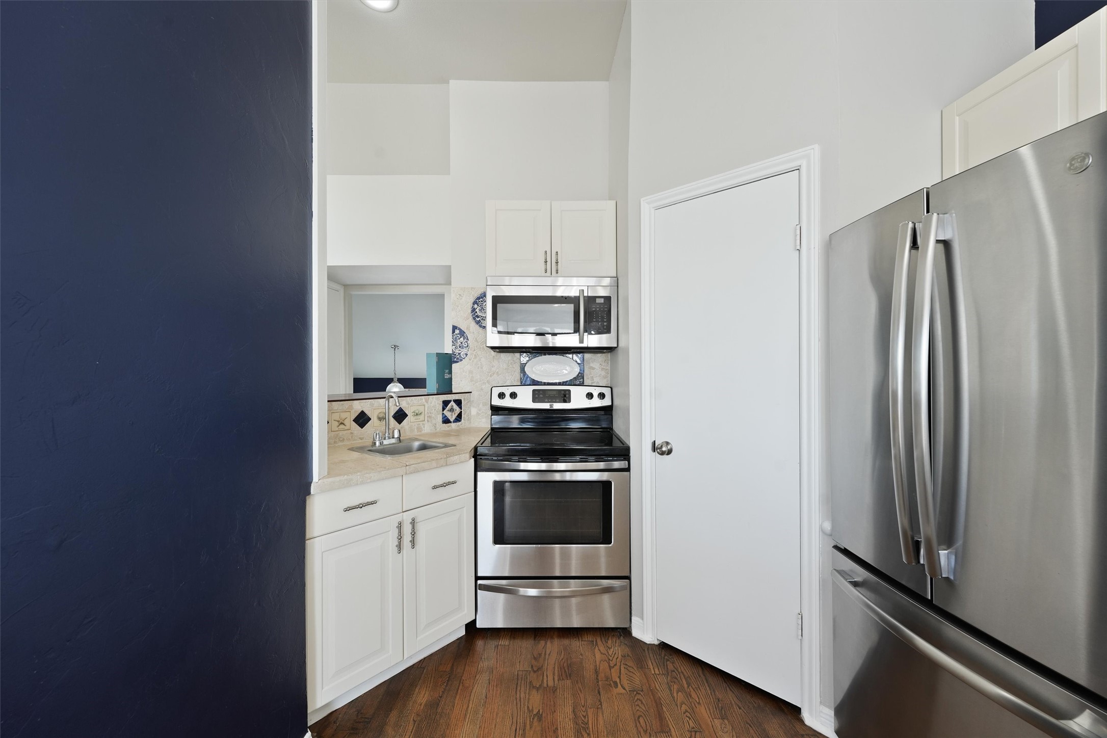 17607 Termini-San Luis Pass Road Galveston, TX 77554 - Photo 15 of 42 Stainless steel appliances and white cabinets are complemented by a playful, coastal-themed backsplash. The efficient layout makes cooking easy, while the open design maintains connection to the rest of the townhome.