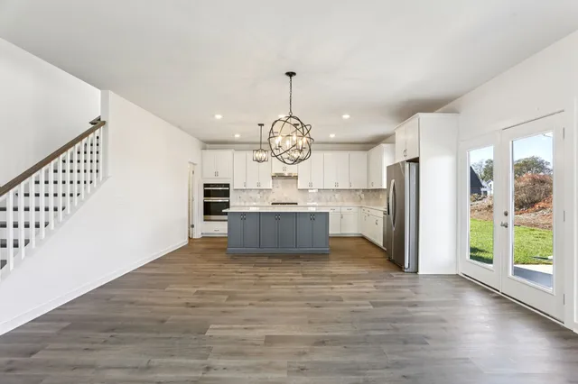 a view of an empty room with wooden floor and fireplace