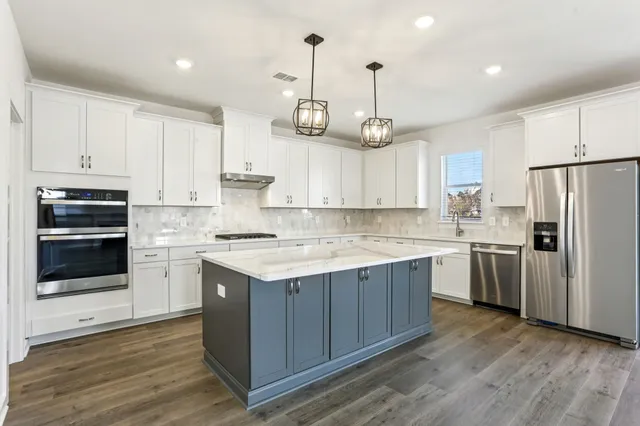 a large kitchen with cabinets wooden floor and stainless steel appliances
