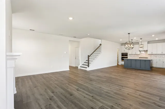 an empty room with wooden floor fireplace and windows