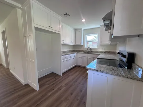 a kitchen with granite countertop a sink cabinets and wooden floor