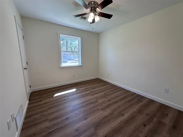 a view of an empty room with window and wooden floor