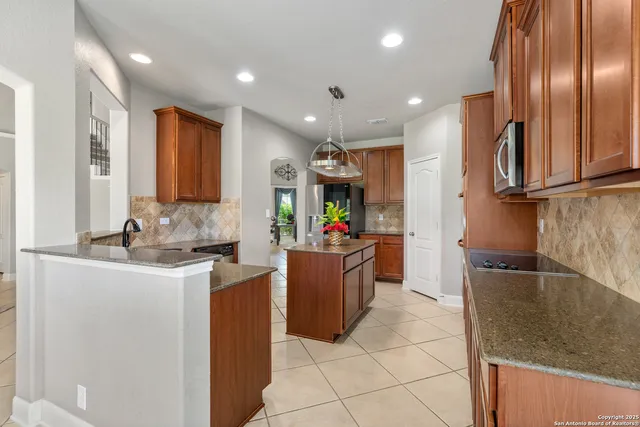 a kitchen with kitchen island granite countertop a refrigerator and a sink
