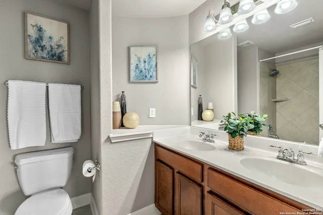 a bathroom with a granite countertop toilet sink and mirror