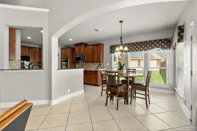 a kitchen with stainless steel appliances kitchen island granite countertop a table chairs and a refrigerator