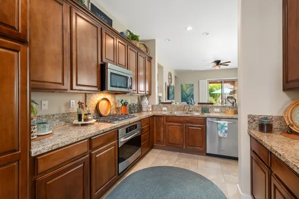 a kitchen with stainless steel appliances granite countertop a sink stove cabinets granite counter tops and a window