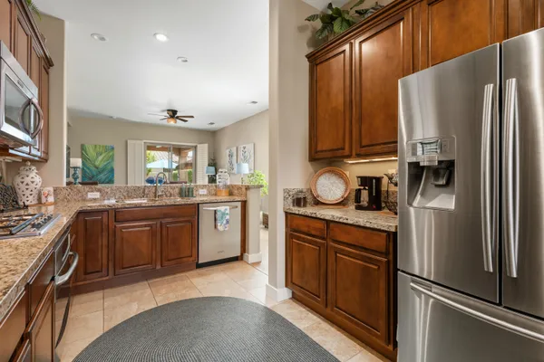 a kitchen with stainless steel appliances granite countertop a refrigerator a stove and a sink