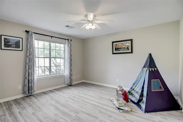 a view of empty room with wooden floor and fan