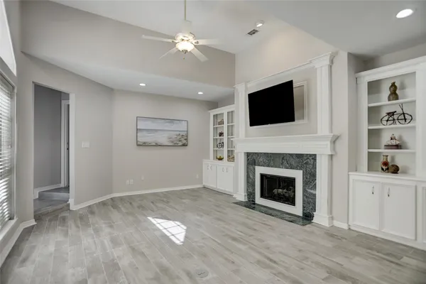 an empty room with windows fireplace and cabinet