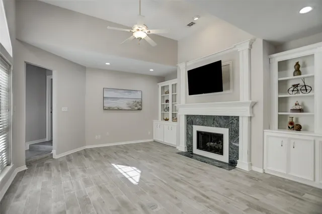 an empty room with windows fireplace and cabinet