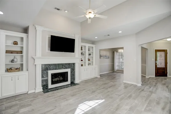 a view of a livingroom with a fireplace a ceiling fan a fireplace and entryway