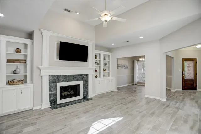 a view of a livingroom with a fireplace a ceiling fan a fireplace and entryway