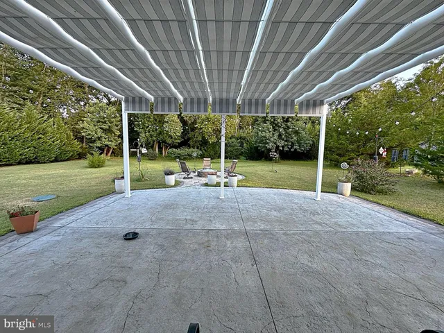 a view of a backyard with table and chairs under a large tree
