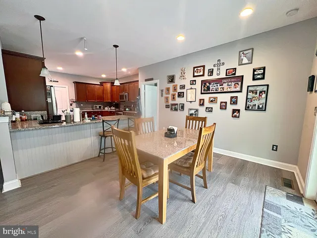 a dining room with stainless steel appliances kitchen island granite countertop a dining table chairs and a refrigerator