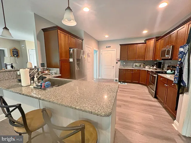 a kitchen with stainless steel appliances granite countertop a stove top oven a sink dishwasher a dining table and chairs with wooden floor