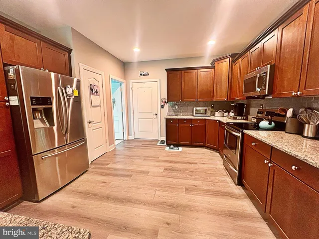 a kitchen with stainless steel appliances granite countertop a refrigerator stove top oven and sink