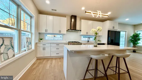 a large white kitchen with a large counter top and stainless steel appliances