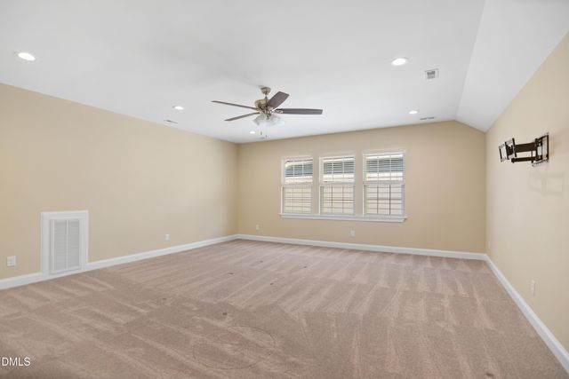 an empty room with windows and ceiling fan