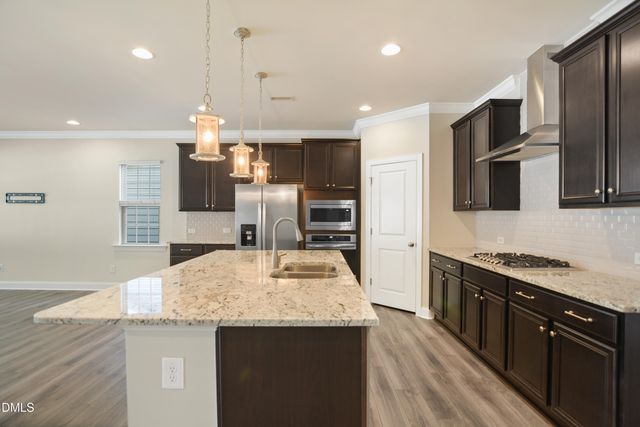 a kitchen with stainless steel appliances granite countertop a sink a stove and a wooden floors