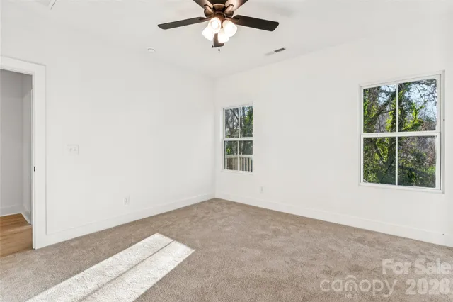 an empty room with windows and fan