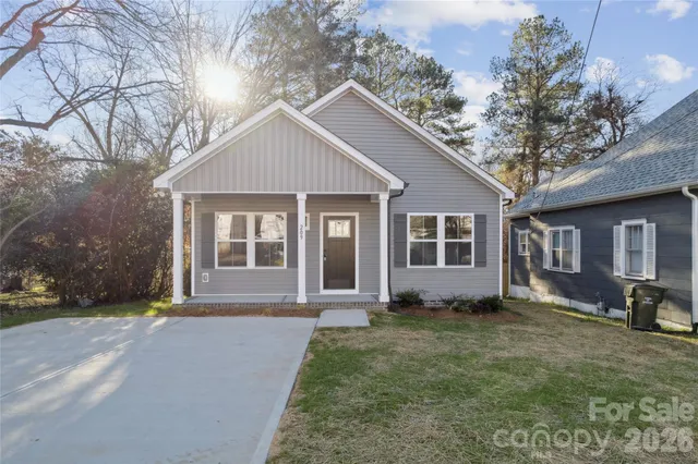a front view of a house with a garden and trees