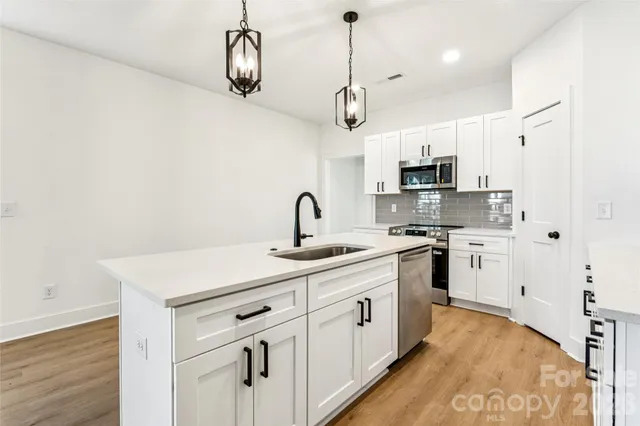 a kitchen with kitchen island white cabinets stainless steel appliances and a counter top