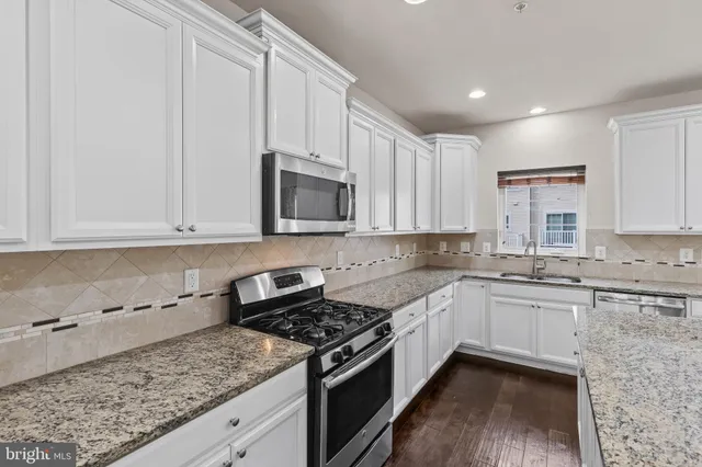 a kitchen with stainless steel appliances granite countertop a stove a sink and a microwave
