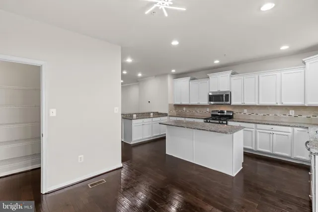 a kitchen with granite countertop white cabinets and white appliances